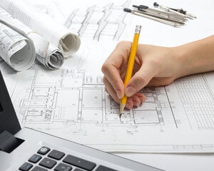 Architect making notes on autocad printout of floorplan.