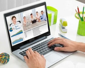 Close-up Of Businessperson Videoconferencing With Colleagues On Laptop In Office