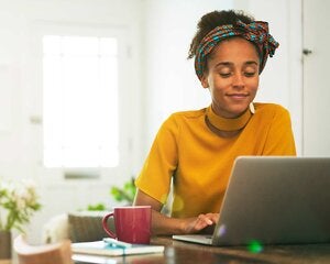 young woman working on her laptop at her home table