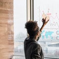 A person reviewing interactive charts and data visualizations on a large window display, illustrating data analysis and decision-making skills.