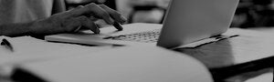 hand typing on a laptop with papers on a desk