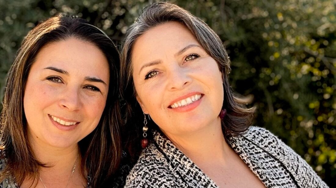 Two alumni women taking picture next to each other