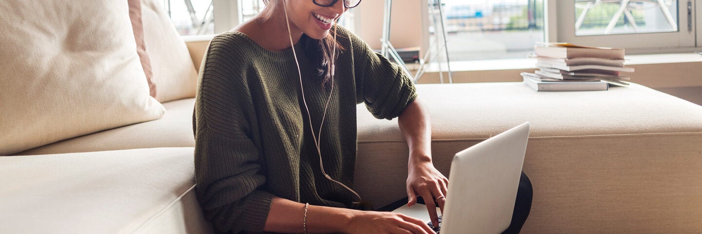 Woman using laptop at home and smiling