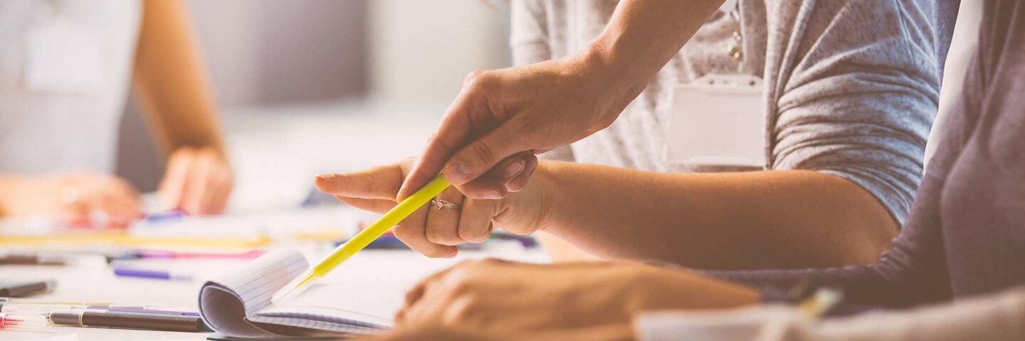 close up of hands pointing with highlighter pen towards paper