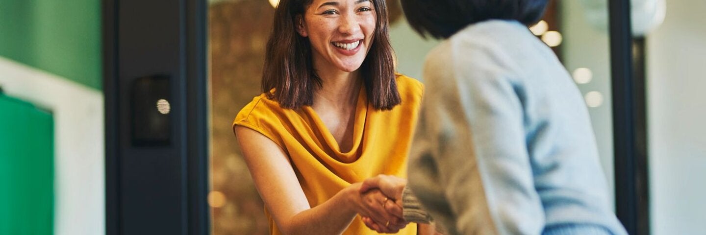 Cheerful businesswomen shaking hands in meeting room