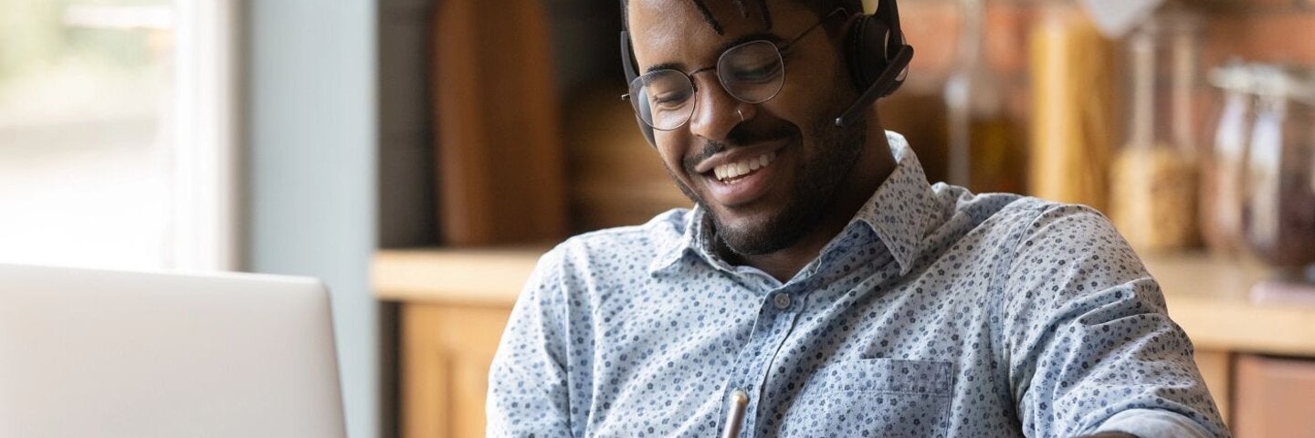 Smiling man in headphones study online on computer