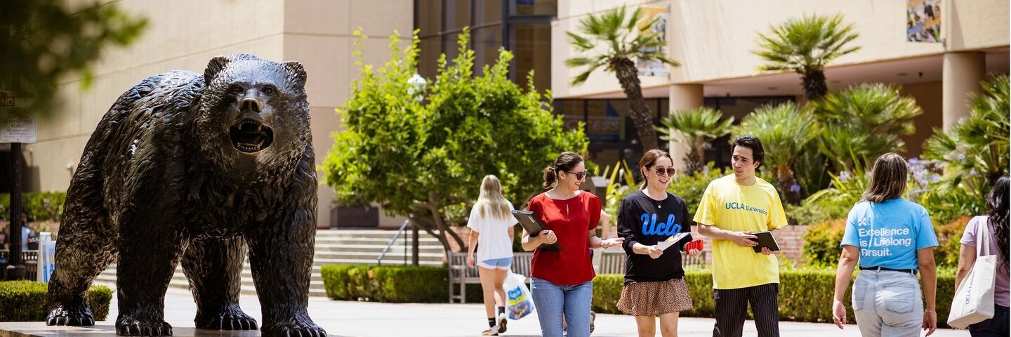 small group of students walking by The Bruin statue on the UCLA campus
