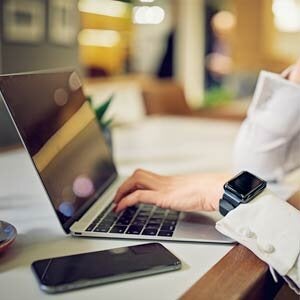 Closeup of woman using laptop with phone on the table
